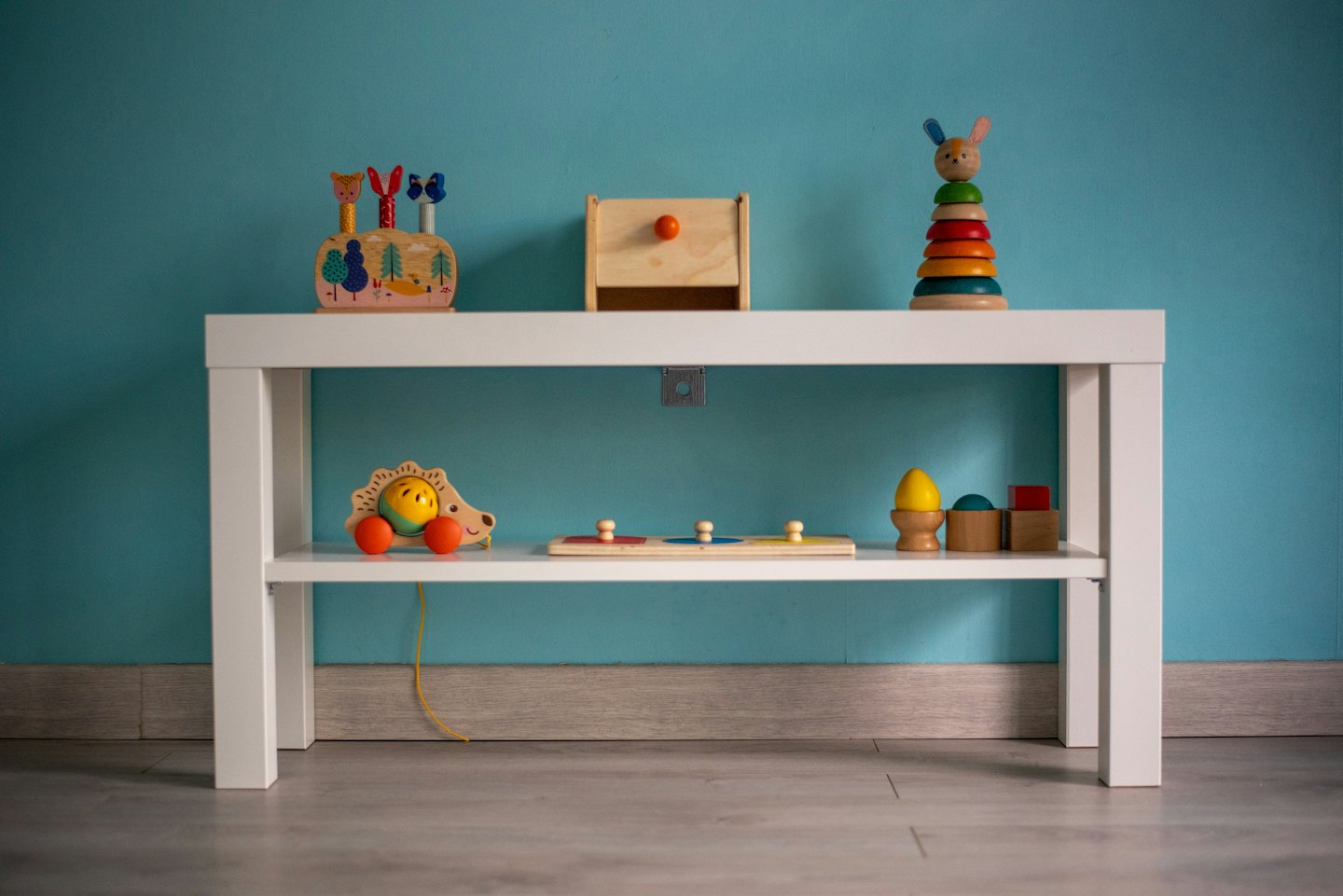 Colorful wooden children's toys organized on a teal wall shelf.