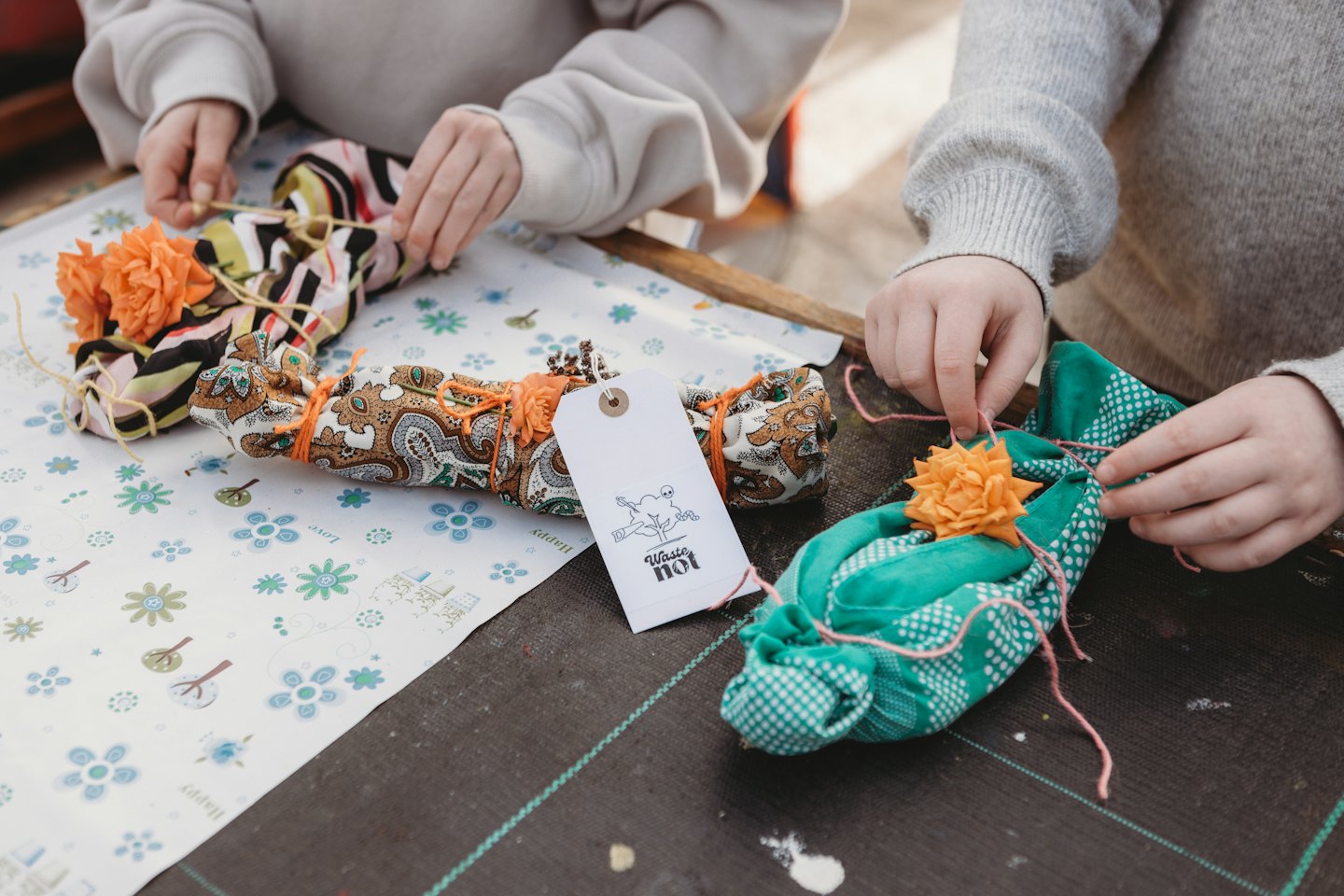 Two people tie patterned fabric with yarn for a craft.